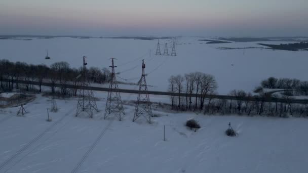 Flygdrönare Visa Power Lines Över Snöiga Fältet Vid Solnedgången — Stockvideo