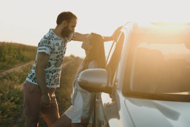 Man and woman standing near car at sunset, middle-aged couple enjoying weekend outside the city