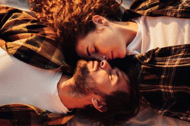 View from above of young couple in love lying facing each other and morning sunlight shines on them