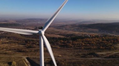 Rüzgâr türbininin panoramik arka planda dönen bıçaklarla hava yoluyla yakın görüntüsü, İHA geriye doğru uçar