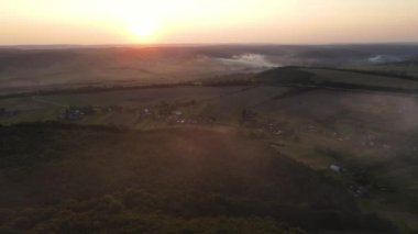 Akşam sisi ve manzaralı günbatımı olan topraklar üzerinde havadan panoramik manzara