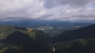 Karpatya dağlarının hava manzarası alçak bulutların arasından ileri doğru uçuyor.