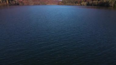 Ufuktaki yüksek dağ ile dağların arasındaki göl manzarası, ters yönde drone 'lar güneşli sonbahar gününün erken saatlerinde su yüzeyinde ortaya çıkıyor.