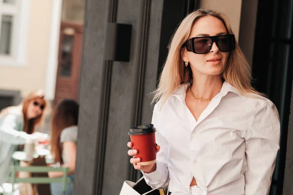 Elegant Woman Coming Out of a Cafe, Holding Cup of Coffee in Hand and Looking Away, Confident Female Entrepreneur Wearing Sunglasses, Coffee to Go Concept