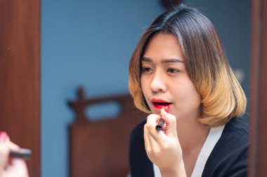 Aynaya bakan Asyalı kadın makyaj yapıyor.