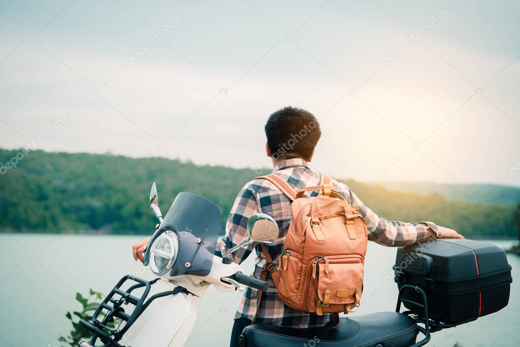 Hipster backpacker riding a motor scooter on road. Travels by scooter slow life on vacation resting time.
