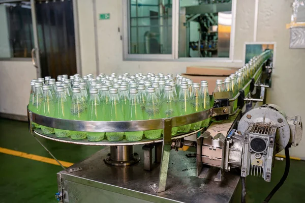 Product of bottled green juice on conveyer belt with automatic machine in beverage processing factory