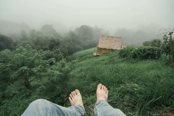 Barefoot man wearing jean hanging on mountain in foggy at rainforest in the morning
