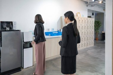 Office employee standing in queue up to drink water form water dispenser on lunch break