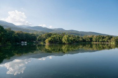 View of Ang Kaew reservoir with mountain and blue sky reflection on sunny day at Chiang Mai