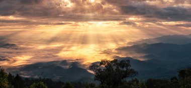 Ulusal parkta sisli bir dağ sırasının üzerinde altın güneş ışığıyla dramatik gökyüzü manzarası. Doi Dam, Wiang Haeng, Chiang Mai, Tayland