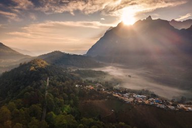 Ban Na Lao Mai, Chiang Mai, Tayland ve Tayland 'daki tropikal yağmur ormanlarının tepelerindeki Doi Luang Chiang Dao dağlarının doğuşunu gösteren hava manzarası.