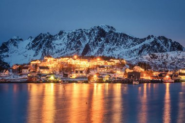Norveç 'in Nordland, Lofoten adalarında karlı dağlarla kıyı şeridinde parlayan balıkçı köyü