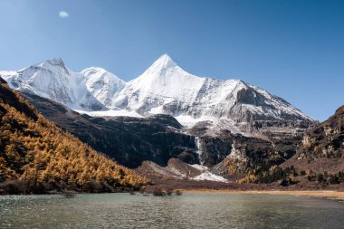 Yangmaiyong 'un kutsal dağının manzarası ve güneşli bir günde dağlık arazi, Yading Doğa Koruma Alanı, Daocheng, Çin