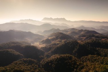 Doi Luang Chiang Dao 'nun güneşli bir günde ulusal parktaki tropikal yağmur ormanlarında üst üste yığılmış dağ katmanı ve sisli havadan görüntüsü.