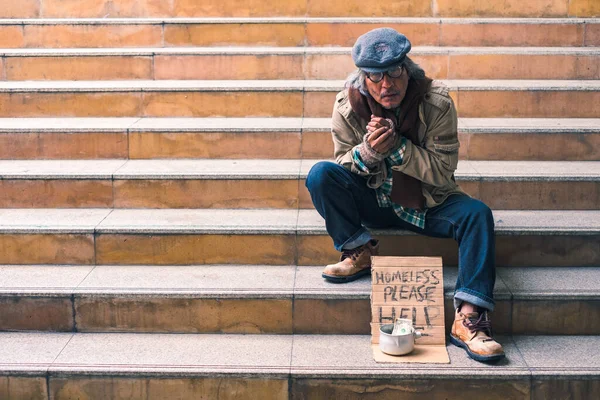 肮脏的无家可归的人坐在楼梯上 手里拿着一块钱的现金 又冷又寂寞 — 图库照片