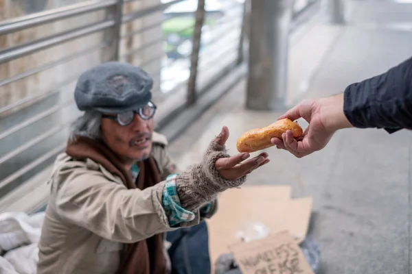 在走廊桥上 无家可归的老人伸出手向捐献者要面包 — 图库照片