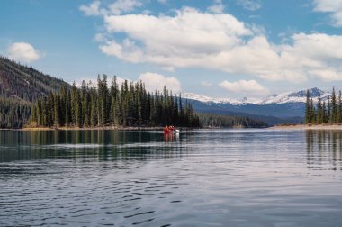 Güneşli bir günde Kanada 'daki Jasper Ulusal Parkı' nda Maligne Gölü 'nde kano yapan turistler. Boş zaman aktivitesi, eğlence arayışı.