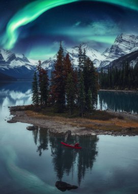 Gezgin adam, gecenin bir yarısı Kanada 'nın Alberta kentinde Jasper Ulusal Parkı' nda Aurora Borealis ile kano yapıyor.