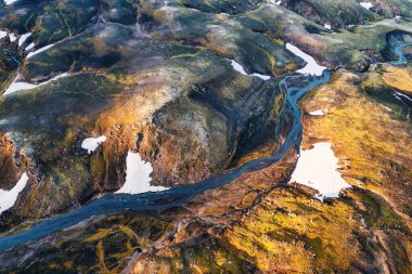 Above of scenic surreal volcanic mountain with river through lava field located remote in Highlands of Iceland on summer