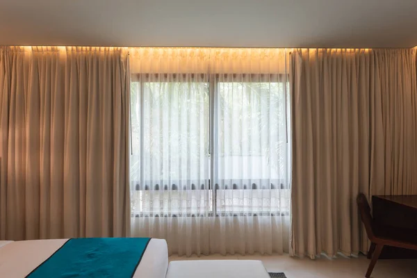 Interior of hotel room with lighting on beige curtain in contemporary bedroom