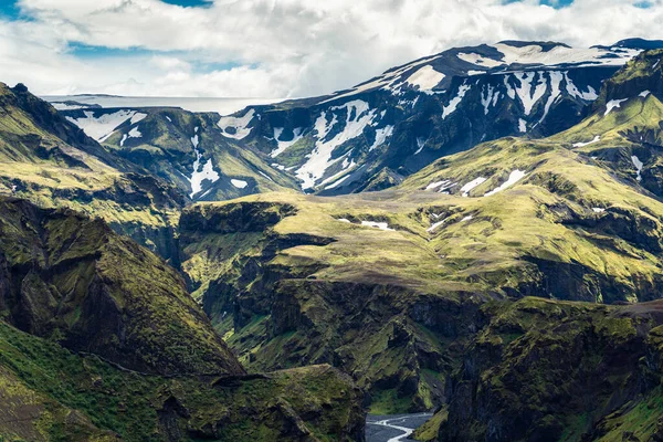 雪に覆われた雄大な緑の山の峡谷とアイスランドのソルスモークで夏のアイスランドのハイランドで川 — ストック写真