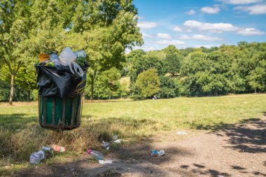 London, UK - July 2020 : Overflowing large rubbish and litter garbage and waste bin  in a nature Park
