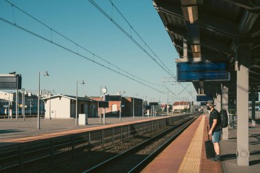 Bydgoszcz, Polonya - Ağustos 2020: Korumacı yüz maskesi takan orta yaşlı erkek adam, boş bir platformda tek başına duruyor planlanan trenin gelmesini bekliyor, covid19 salgını sırasında seyahat ediyor.