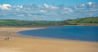 Llanstefan, Wales - Mayıs 2021: Aile, Galler 'in güneyindeki alçak gelgitte LLansteffan plajında geniş bir kumsalda yürüyor.