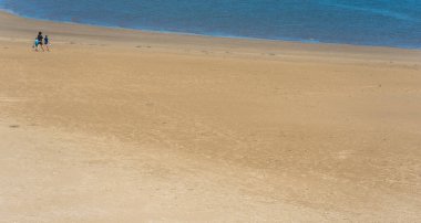 Llanstefan, Wales - Mayıs 2021: Güney Galler 'deki alçak gelgitte LLansteffan sahilinde yürüyen bir ailenin panoramik görüntüsü