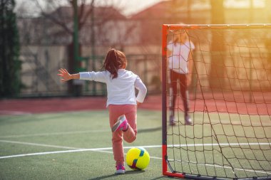Güneşli bahar gününde futbol oynayan mutlu küçük kız. Çocukluk, eğlence oyunları ve insanların konsepti.