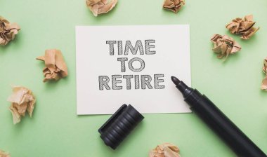 İşaretleyici yanında buruşuk kağıt parçalarıyla birlikte beyaz bir çıkartma üzerinde emekli olmak için zaman yazar.