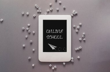 Gri bir arka planda dağınık harflerle ONLINE okul laptopuyla yazılmış. İnternet aracılığıyla eğitim kavramı.