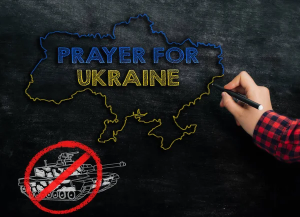Дівчинка малює карту України з текстом "Молитва за Україну" на дошці — стокове фото