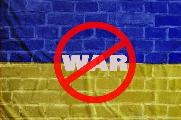 Прапор України на цегляній стіні з текстовою війною, викресленою червоною лінією. Концепція заклику припинити бойові дії — стокове фото