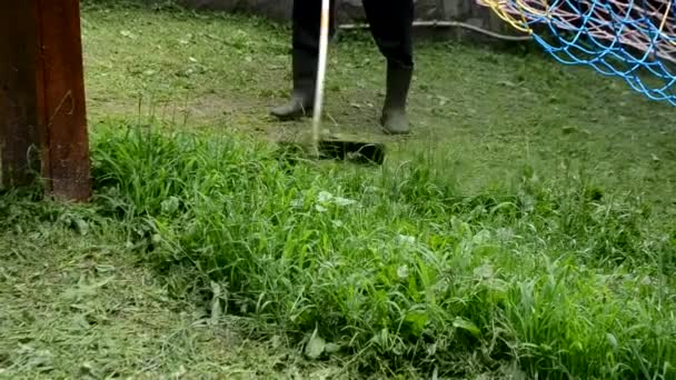 Mann mäht wildes grünes Gras mit Gasmäher im Hinterhof Beine des Hausherrn und Ausrüstung für die Pflege des Landhausgebiets Nahaufnahme