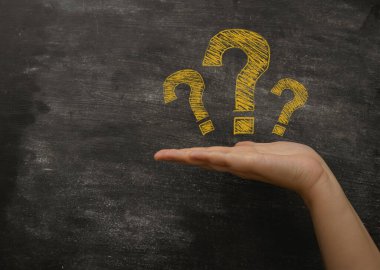 Hand palm with yellow question marks near blackboard closeup. Info service for business clients. Tutorial and support for company customers