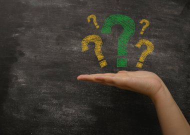 Avuç içinde sarı renkli soru işaretleri olan karatahtaya yakın çekim. Bilgi ve popüler cevaplar arıyorum. Eğitim ve iş hizmetleri