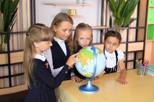 Crianças de uniforme escolar com um globo no escritório. — Fotografia de Stock