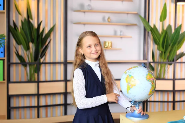 Retrato de uma menina de uniforme escolar com um globo nas mãos. — Fotografia de Stock