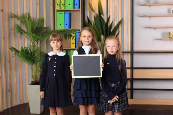 Três meninas estão segurando um quadro de desenho em uma moldura. Imagens De Bancos De Imagens