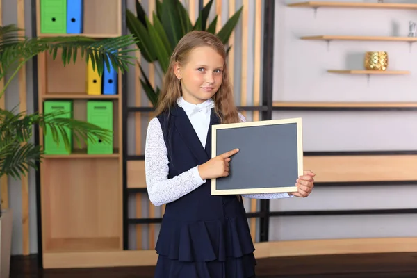 Uma menina segura em sua mão uma prancha de desenho em uma moldura. Imagens De Bancos De Imagens Sem Royalties