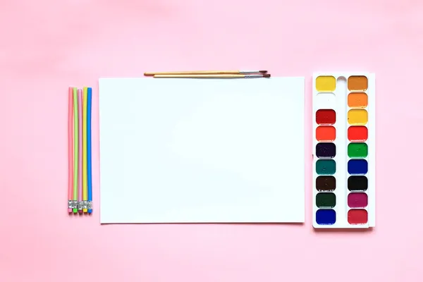 Um conjunto de tintas e lápis para desenhar em um fundo rosa. Fotos De Bancos De Imagens