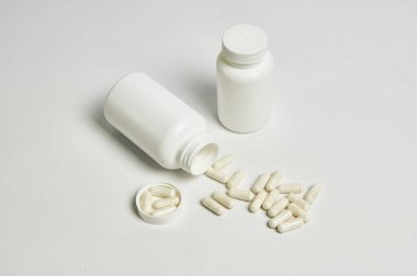 Beyaz arka planda ilaç şişesinden akan beyaz ilaç hapları..