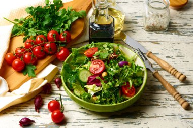 Kiraz domatesli taze salata, roka, salatalık, soğan ve nohut, zeytinyağı ve ahşap bir masada balzamik sosuyla birlikte..