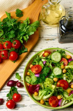 Kiraz domatesli taze salata, roka, salatalık, soğan ve nohut, zeytinyağı ve ahşap bir masada balzamik sosuyla birlikte..