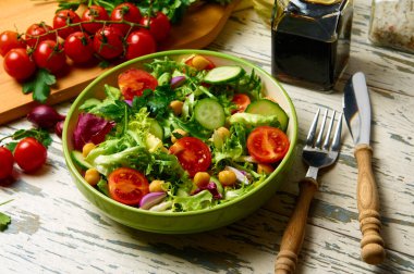 Kiraz domatesli taze salata, roka, salatalık, soğan ve nohut, zeytinyağı ve ahşap bir masada balzamik sosuyla birlikte..