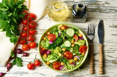 Kiraz domatesli taze salata, roka, salatalık, soğan ve nohut, zeytinyağı ve ahşap bir masada balzamik sosuyla birlikte..