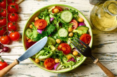 Kiraz domatesli taze salata, roka, salatalık, soğan ve nohut, zeytinyağı ve ahşap bir masada balzamik sosuyla birlikte..