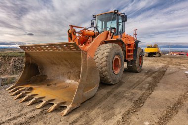 İnşaat alanında kazıcı, toprak taşıma işi yapıyor.